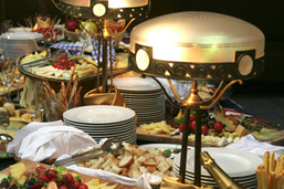 Piles of plates and various food dishes on a table. 