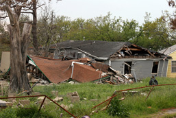 A demolished human construction and a damaged fence following a hurricane.