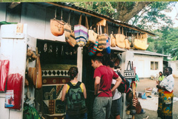 Three tourists look at a local artcraft outdoor stand.