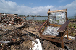 A pile of debris, of which a chair, along some coastline.